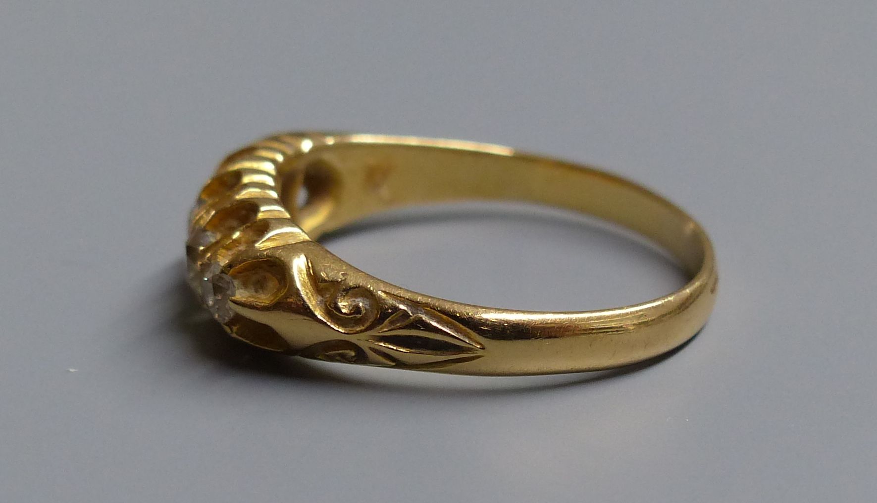 An Edwardian 18ct gold and graduated five stone diamond set half hoop ring, size P/Q, gross 4 grams.